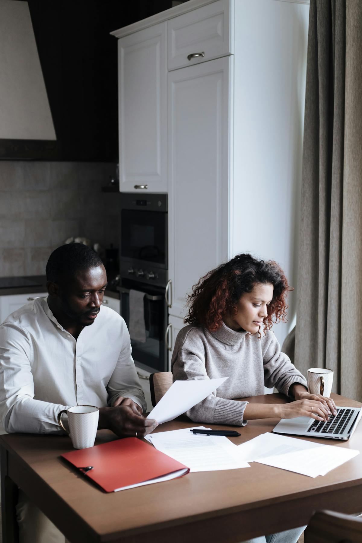 A couple reviewing documents and a laptop at home.